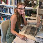 Author Madeline Te Whiu working at her desk, surrounded by editorial notes and bookcases.